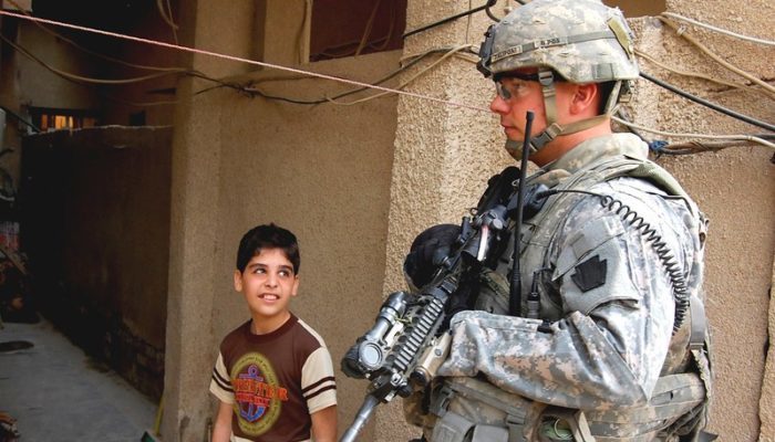 Sgt. Aaron Zaliponi, an infantry squad leader, with 56th Stryker Brigade Combat Team, 28th Infantry Division, Pennsylvania Army National Guard, passes a young boy while searching for illegal weapons cache, Feb. 9. Zalioponi, a native of Butler, Pa., partnered with Al Salaam Iraqi police officers during the combined clearance operation. PHOTO: U.S. Government