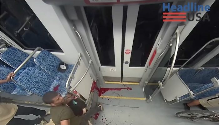 A fellow passenger attempts to render aid to the Ukrainian refugee who was stabbed to death on a train in Charlotte --- but it was far too late. PHOTO: Screenshot from footage obtained by Headline USA